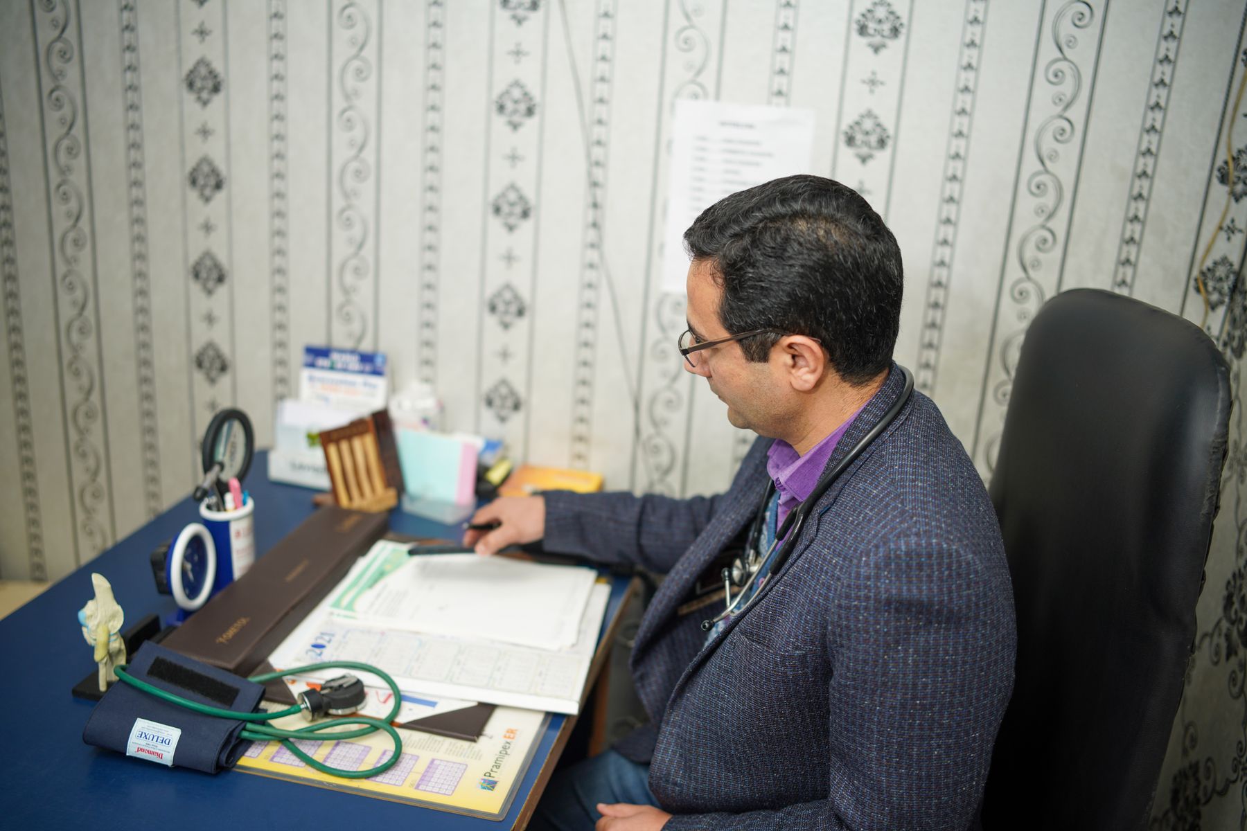 Medical examiner reviewing health documentation at a clinic desk